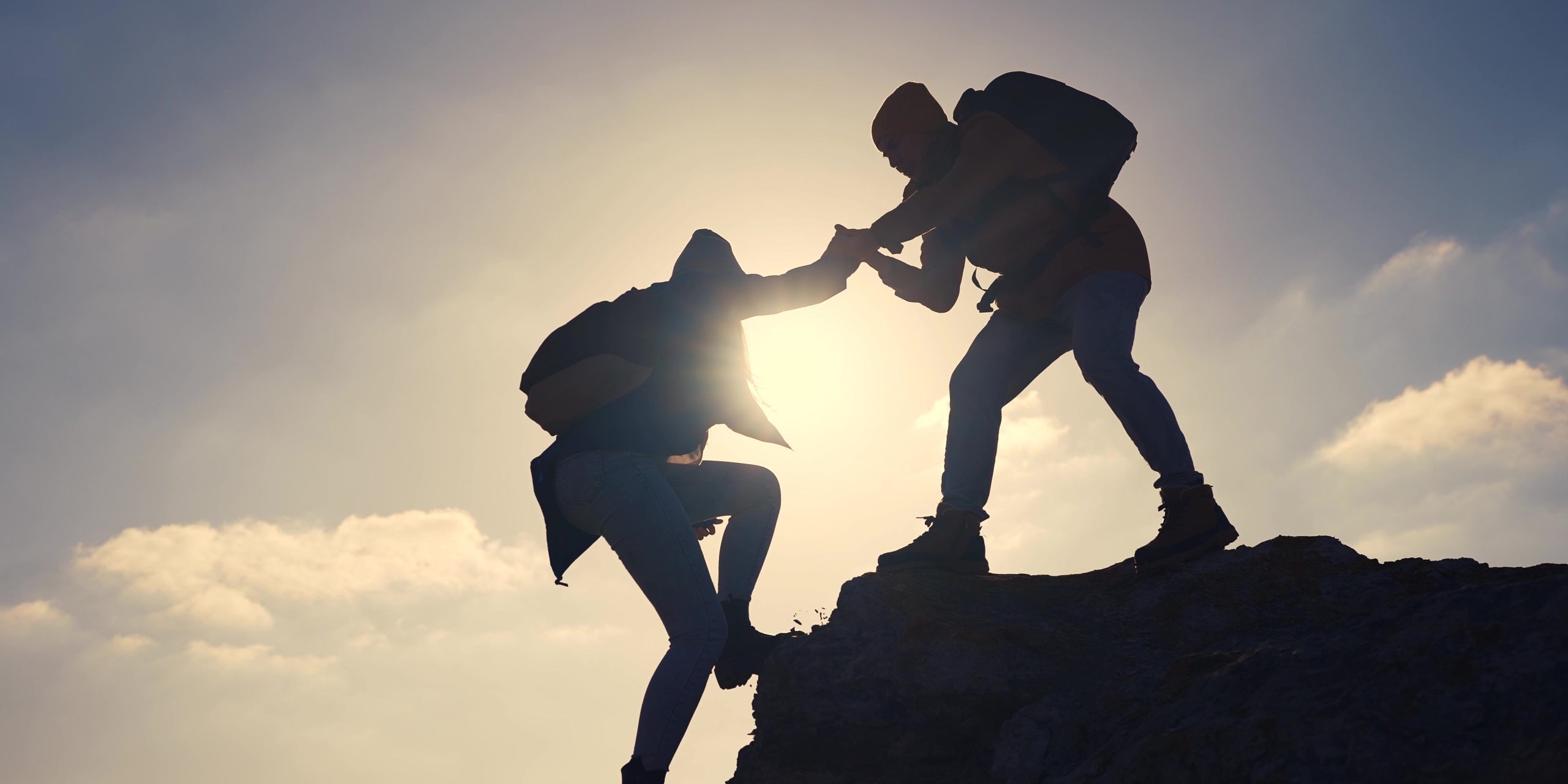Una persona ayuda a otra a llegar a la cima
