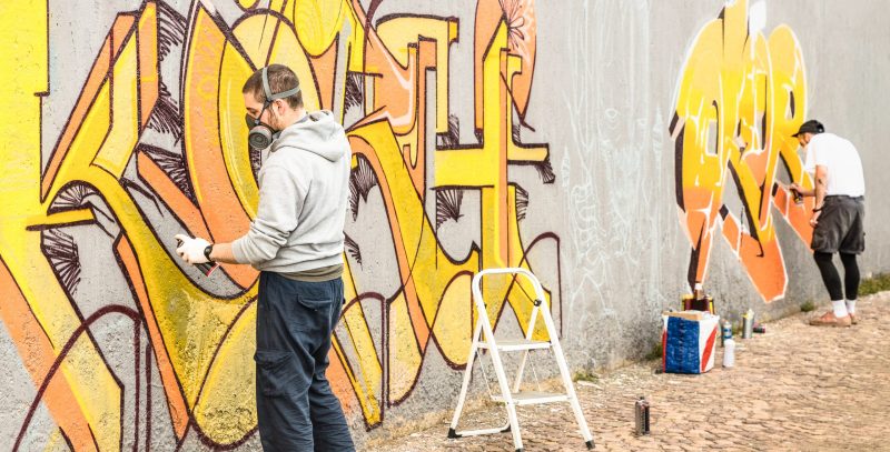 Dos jóvenes haciendo un graffiti en un muro