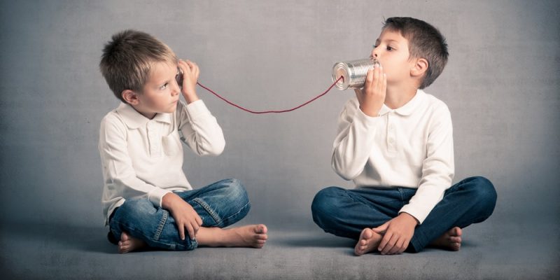 dos niños intentan comunicarse con dos latas y un hilo