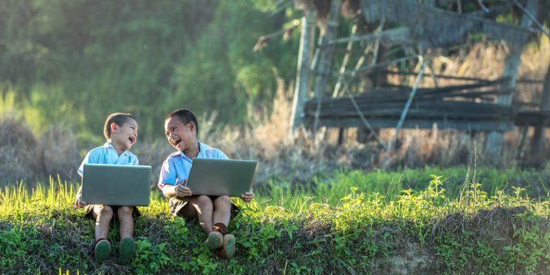 dos niños utilizan computadoras portátiles