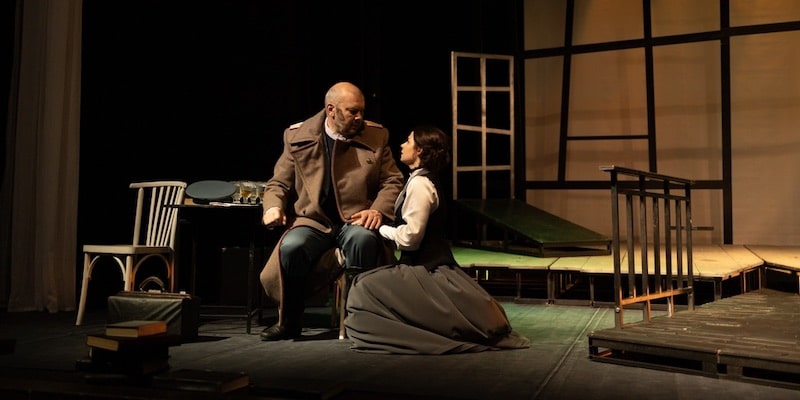 Dos actores representan personajes sobre un escenario.