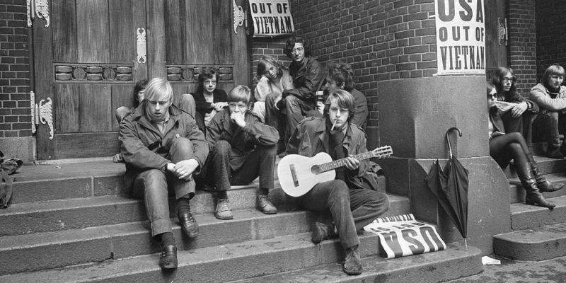 Foto en blanco y negro de un grupo de jovenes sentados en los escalones de un edificio