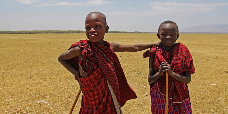 Dos niños de Tanzania sonríen, vistiendo sus ropas tradicionales.