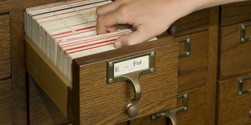 Una persona busca información bibliográfica en un fichero.