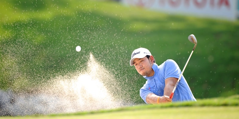 El jugador de golf Chinnarat Phadungsil logra con un golpe quitar la bola de un banco de arena.