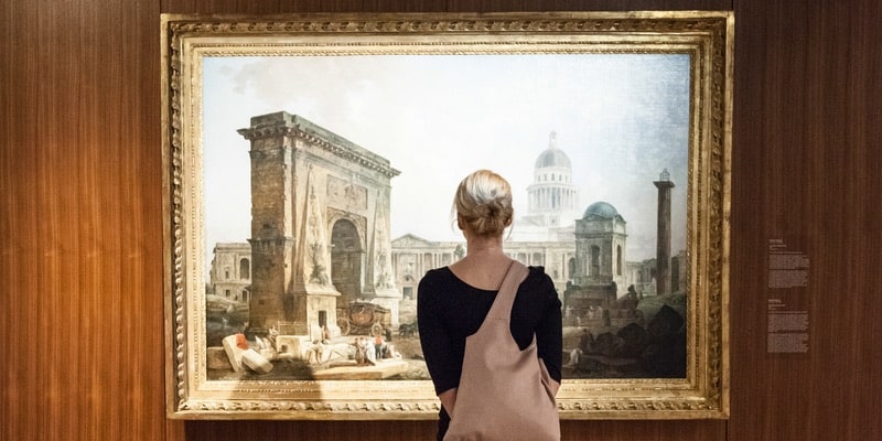 Una mujer observa una obra de arte pictórica.