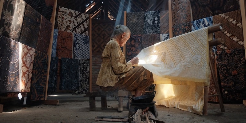 Una anciana decora telas a mano en la producción artesanal.