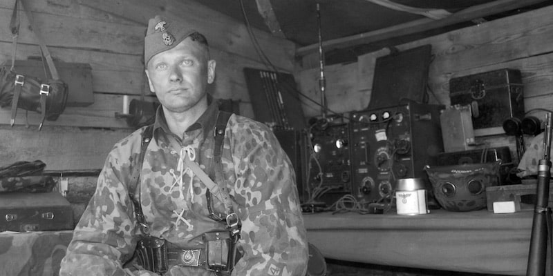 Un soldado está rodeado de sus herramientas militares entre las que se encuentra la radio.