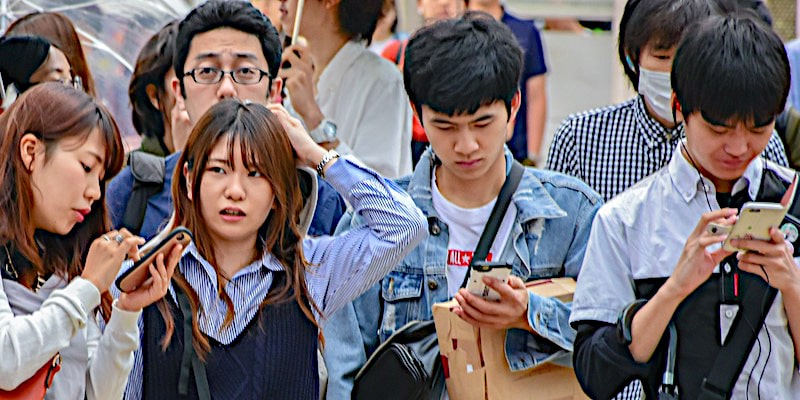Un grupo de jóvenes mira sus teléfonos en la calle mientras una de ellos muestra preocupación.