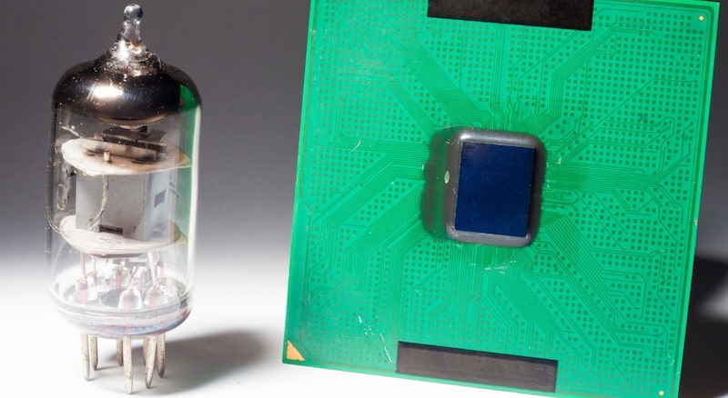 Una antigua válvula de vacío se encuentra junto a un microprocesador.