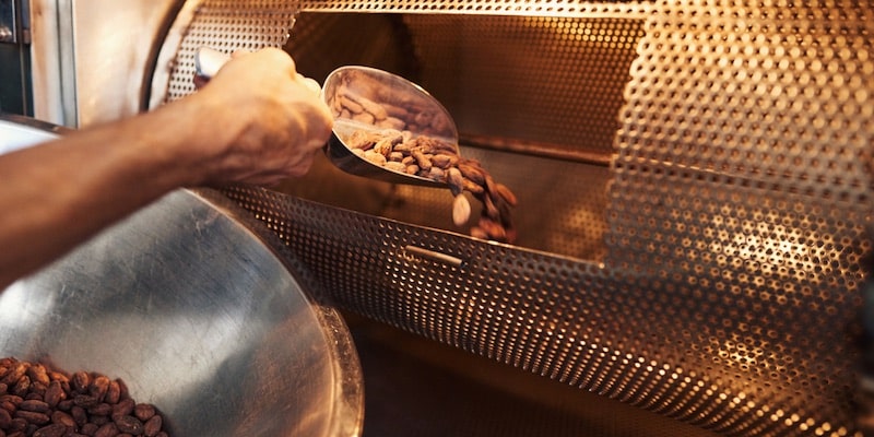 Un trabajador introduce granos de cacao en la tostadora.
