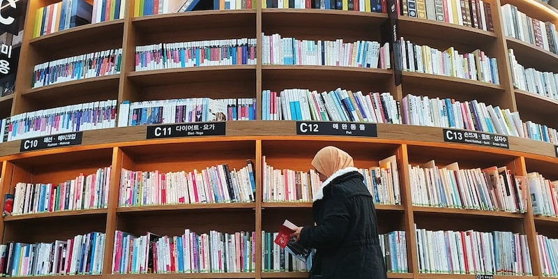 Una investigadora lee un libro en una enorme biblioteca.