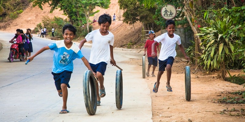 Un grupo de niños juega con neumáticos viejos, usándolos como aros.