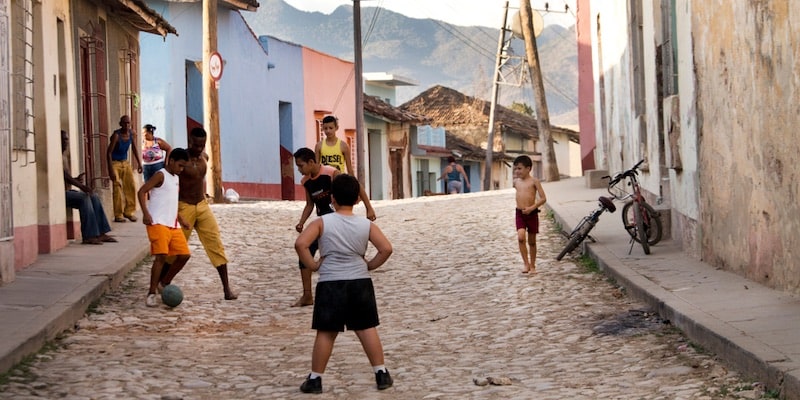 Un grupo de niños juega al fútbol en la calle.