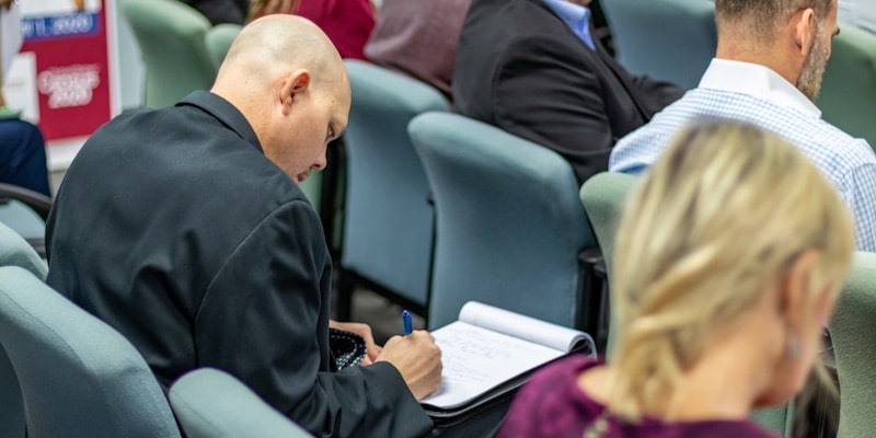 Un hombre toma notas durante una reunión para realizar la minuta.