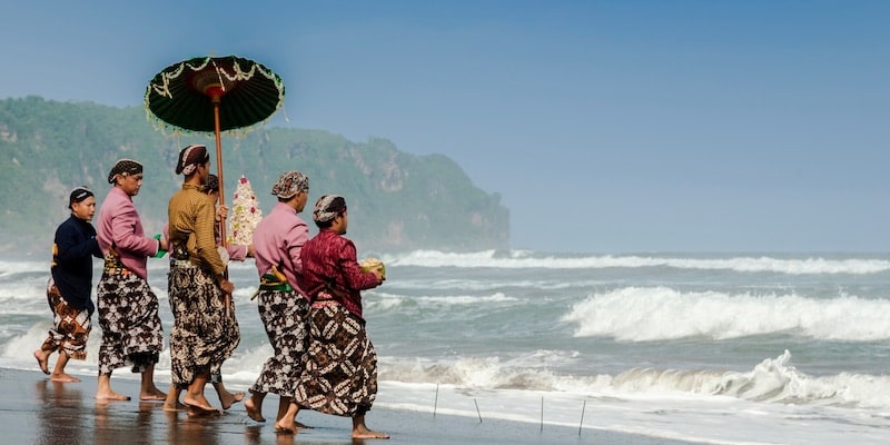 Un grupo de personas lleva ofrendas al mar.