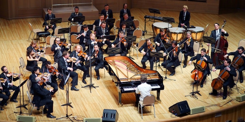 Un concierto de orquesta tiene en el centro al piano de cola.