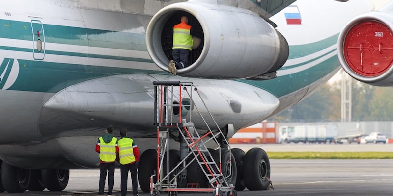 Un grupo de operarios revisa la turbina de un avión.