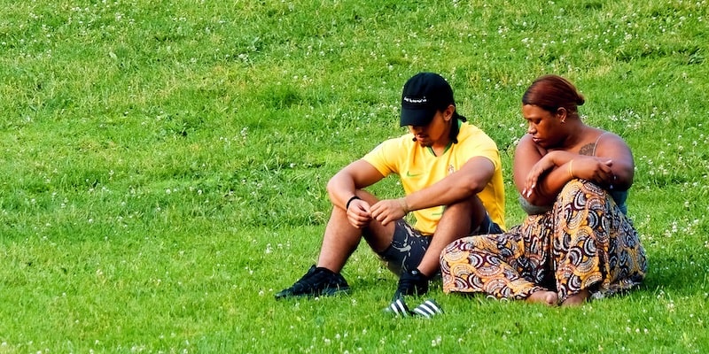 Dos jóvenes en el parque reflexionan preocupados sobre un dilema.