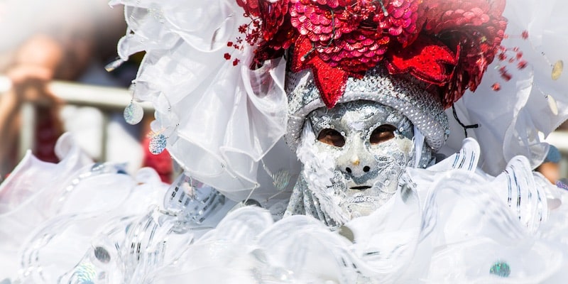 El atuendo y máscara de un participante del carnaval de Barranquilla combina el blanco brillante y el rojo.