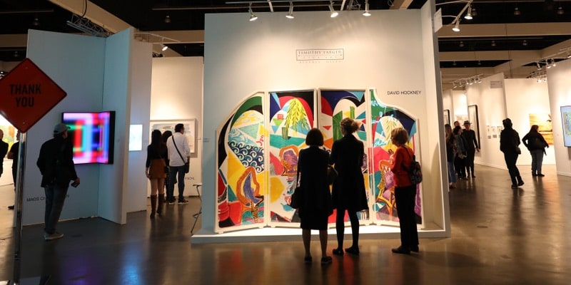 Los visitantes observan obras de artes visuales contemporáneas en un museo.