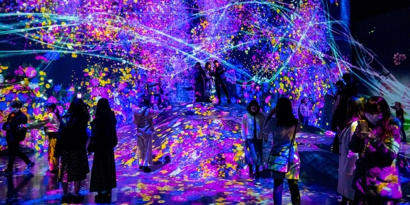 Los visitantes están rodeados de proyecciones de luces de colores en el museo de arte digital de Tokio.