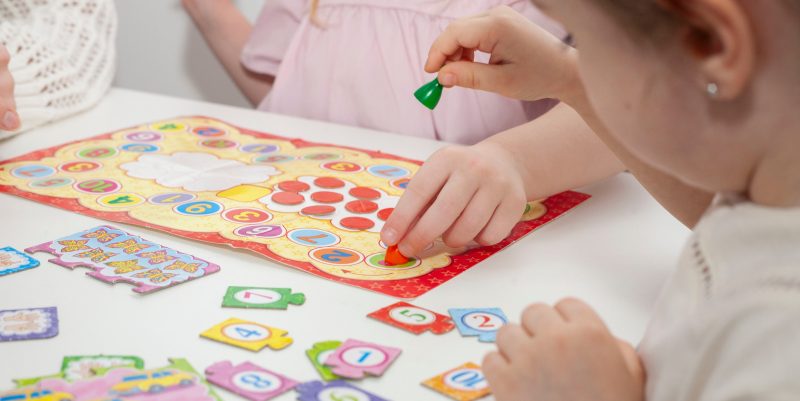 Niños juegando un juego de mesa con fichas de colores.