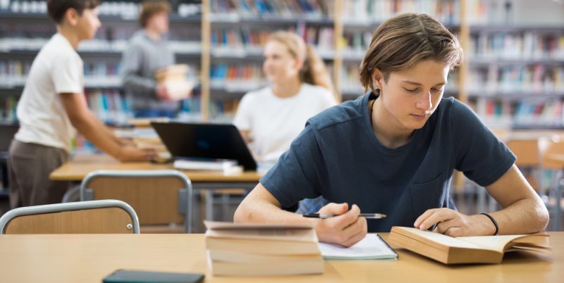 Joven estudiando en la biblioteca.
